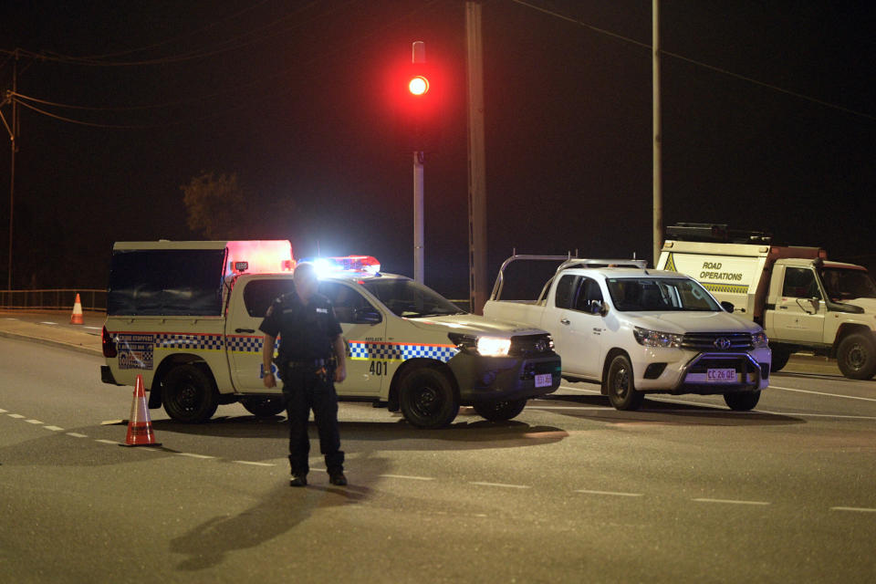 A police car is seen at the intersection of McMinn Street and Stuart Highway in Darwin at night following a shooting.