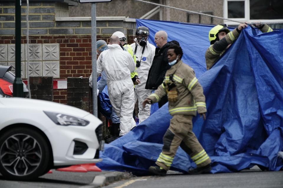 Firefighters and forensic investigators outside the house on Friday (PA)