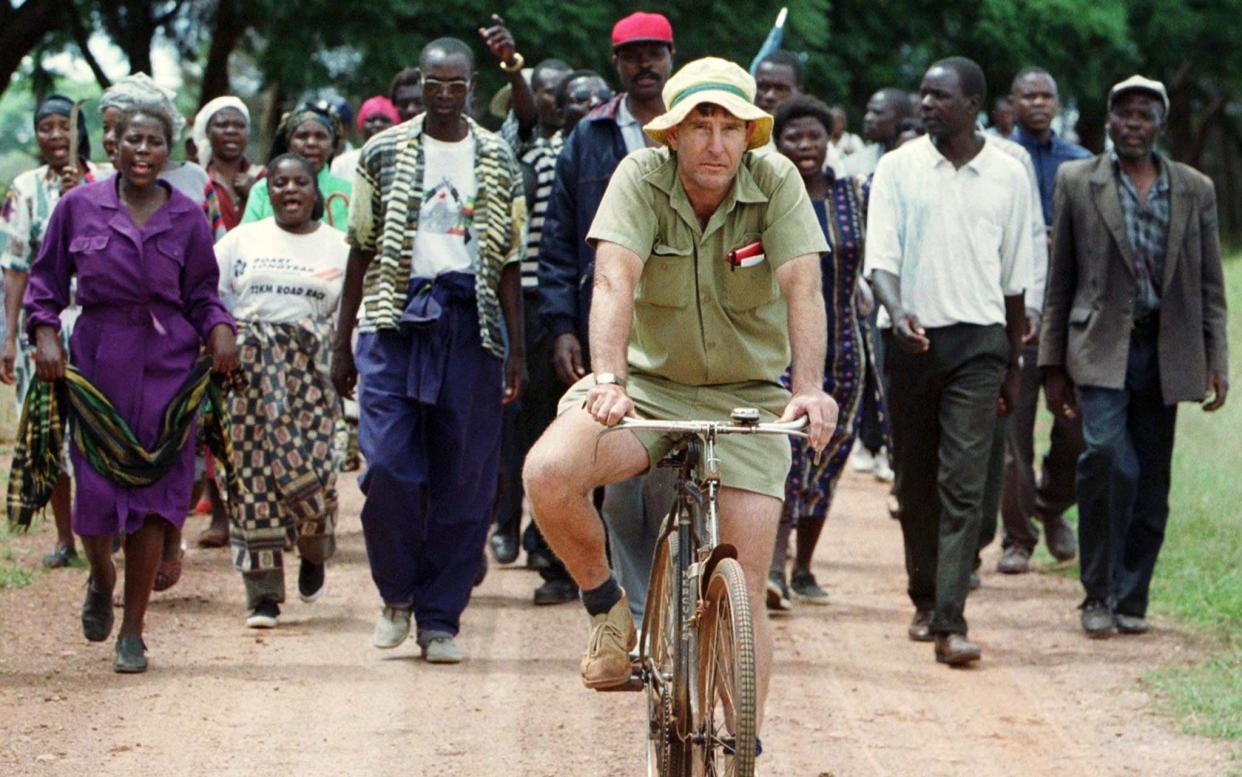 Zimbabwean commercial farmer Tommy Bayley rides an old bicycle ahead of war veterans and villagers who invaded his farm Danbury Park, 30 kilometres (18.6 miles) northwest of Harare, to an abandoned house to use as temporary shelter April 8, 2000. Zimbabwe was thrown into turmoil in February when Robert Mugabe's supporters and self-styled veterans of the 1970s war of liberation invaded white-owned farms, demanding land they said had been illegally taken away by colonisers. - Howard Burditt/REUTERS