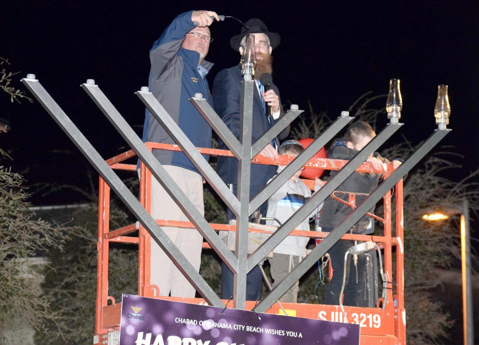 Panama City Beach Mayor Mark Sheldon, left, helps Rabbi Mendel Havlin of the Chabad of Panama City Beach light a 12-foot-tall menorah during the third annual Grand Menorah Lighting Event on Monday night.