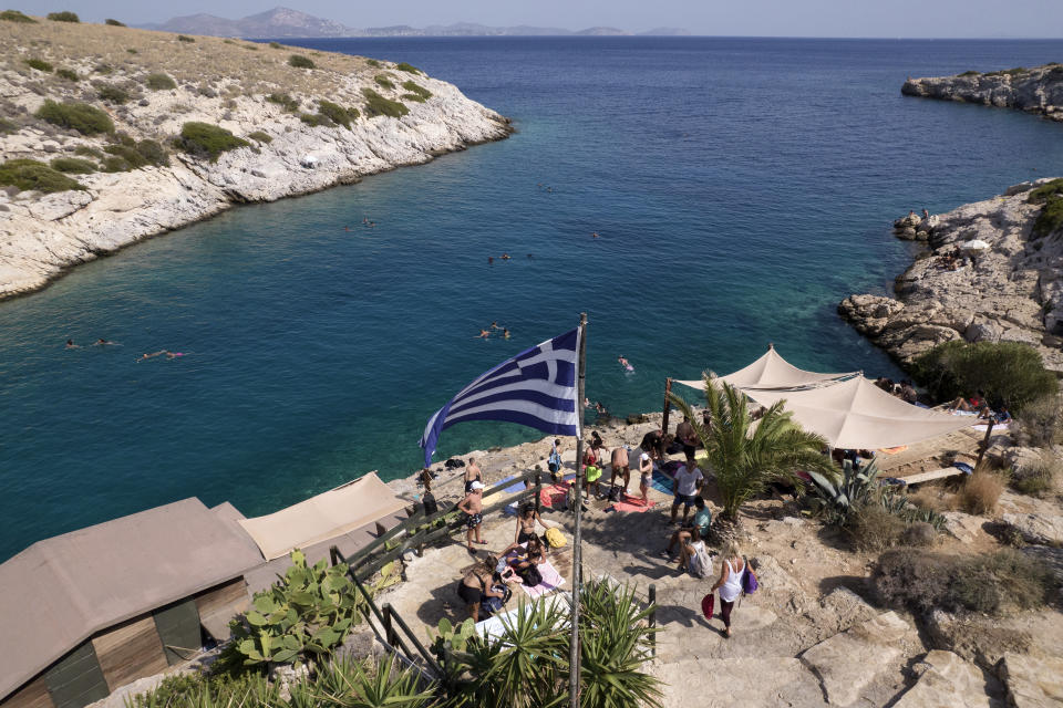 People are pictured next to a beach bar at Vouliagmeni suburb, southwest of Athens, on Thursday, July 29, 2021. One of the most severe heat waves recorded since 1980s scorched southeast Europe on Thursday, sending residents flocking to the coast, public fountains and air-conditioned locations to find some relief, with temperatures rose above 40 C (104 F) in parts of Greece and across much of the region. (AP Photo/Yorgos Karahalis)