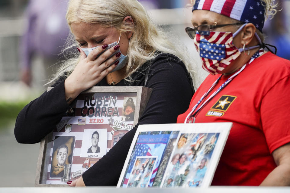 Jo Anne Barbara cries while holding a frame collage of Ruben Correa, a fallen FDNY firefighter, at the National September 11 Memorial and Museum, Friday, Sept. 11, 2020, in New York. Americans will commemorate 9/11 with tributes that have been altered by coronavirus precautions and woven into the presidential campaign. (AP Photo/John Minchillo)