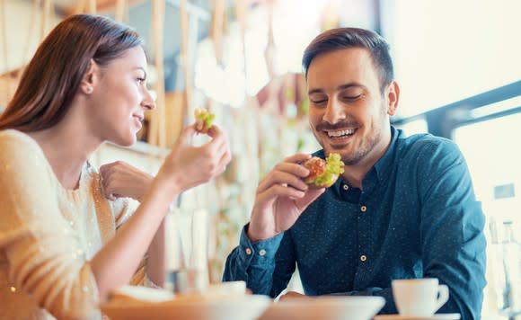 Man and woman eating breakfast with coffee.