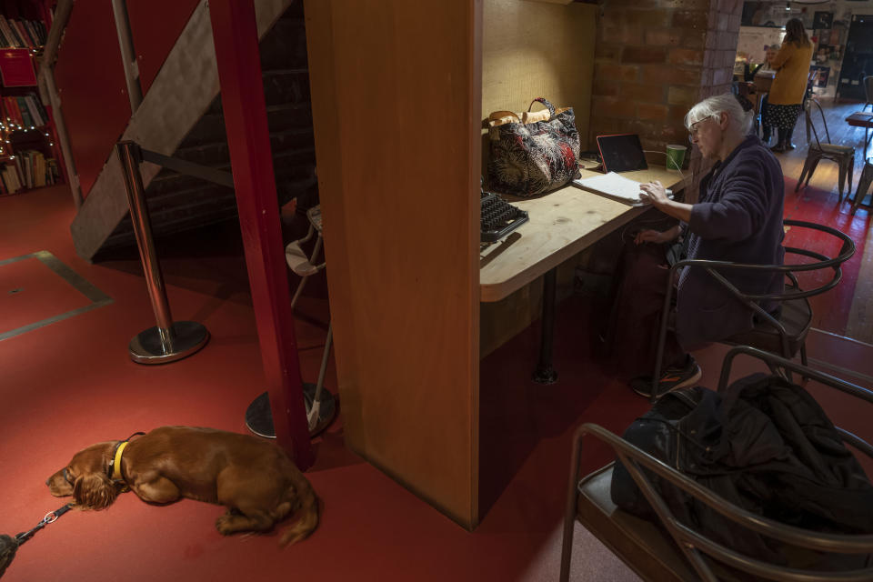 Anne Bolger works at the Other Place theater, in Stratford-upon-Avon, Warwickshire, England, Tuesday, Feb. 28, 2023. The foyer of the Other Place theater in Shakespeare's birthplace of Stratford-upon-Avon is a cozy refuge from winter. One day a week the theater becomes a "warm hub," set up by the Royal Shakespeare Company to welcome people who may be struggling to heat their homes because of sky-high energy prices. (AP Photo/Kin Cheung)