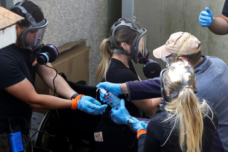 Members of a Servpro cleaning crew use hand sanitizer as they exit the Life Care Center of Kirkland, the Seattle-area nursing home at the epicenter of one of the biggest coronavirus outbreaks in the United States, in Kirkland