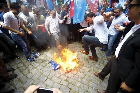 Demonstrators set fire to a Chinese flag during a protest against China near the Chinese Consulate in Istanbul, Turkey July 5, 2015. REUTERS/Osman Orsal