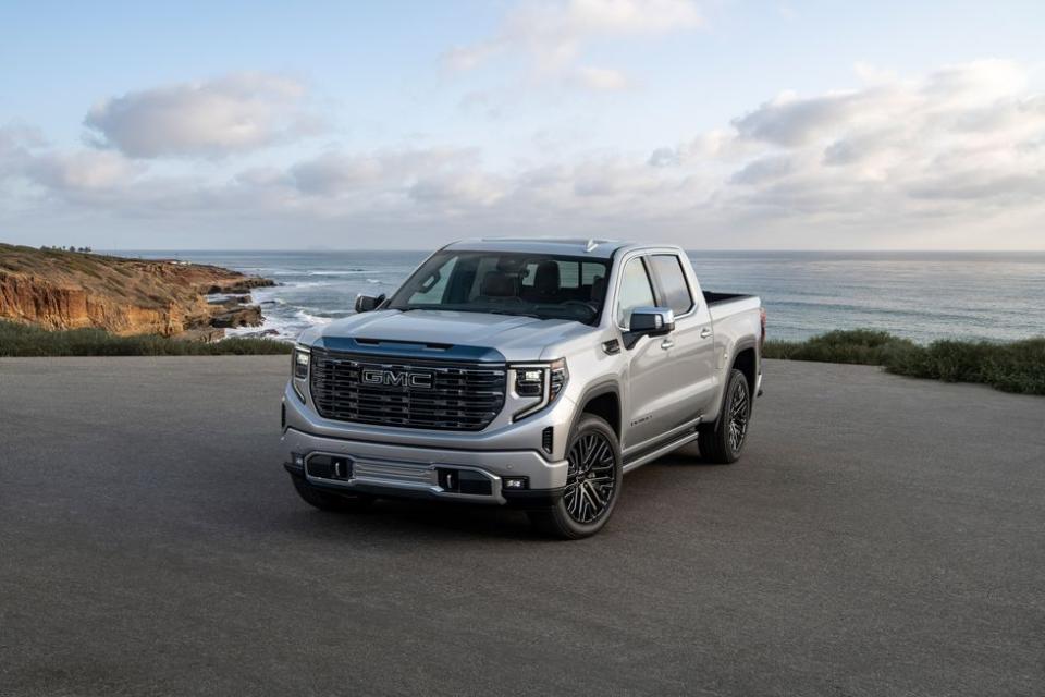 a silver truck parked on a road by a body of water