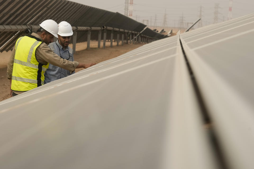Engineers talk next to photovoltaic solar panels at Benban Solar Park, one of the world's largest solar power plants in the world, in Aswan, Egypt, Oct. 19, 2022. The Arab world’s most populous country is taking steps to convert to renewable energy. But the developing country, like others, faces obstacles in making the switch. (AP Photo/Amr Nabil)