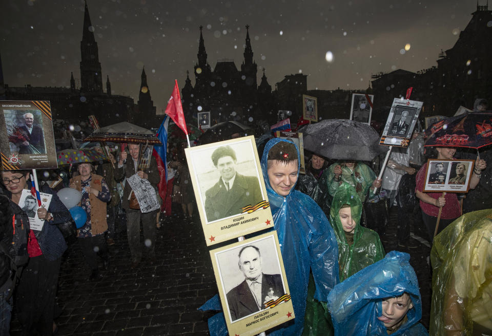 People carry portraits of relatives who fought in World War II under heavy rain during the Immortal Regiment march through Red Square celebrating 74 years since the victory in WWII in Red Square in Moscow, Russia, Thursday, May 9, 2019. (AP Photo/Pavel Golovkin)