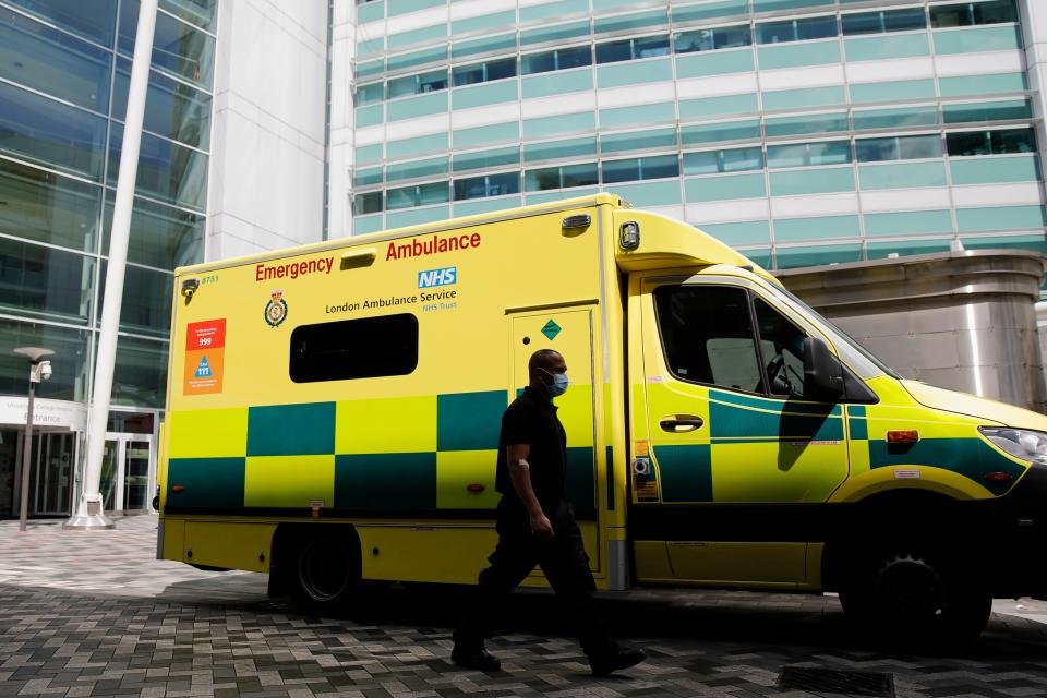 A man wearing a face mask walks past an ambulance at University College Hospital in London on July 17, 2020. - Boris Johnson said on July 17 he hoped Britain would "return to normality" by November despite being badly affected by the coronavirus and predictions of a second wave of cases during winter months. Johnson announced that to prepare for a possible winter spike in cases the state-run National Health Service (NHS) would receive an extra £3 billion ($3.8 billion, 3.3 million euros). (Photo by Tolga AKMEN / AFP) (Photo by TOLGA AKMEN/AFP via Getty Images)