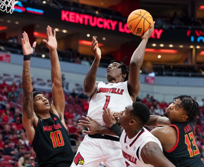 U of L's Mike James (1) shoots between two Maryland defenders during their game at the Yum Center in Louisville, Ky. on Nov. 29, 2022.