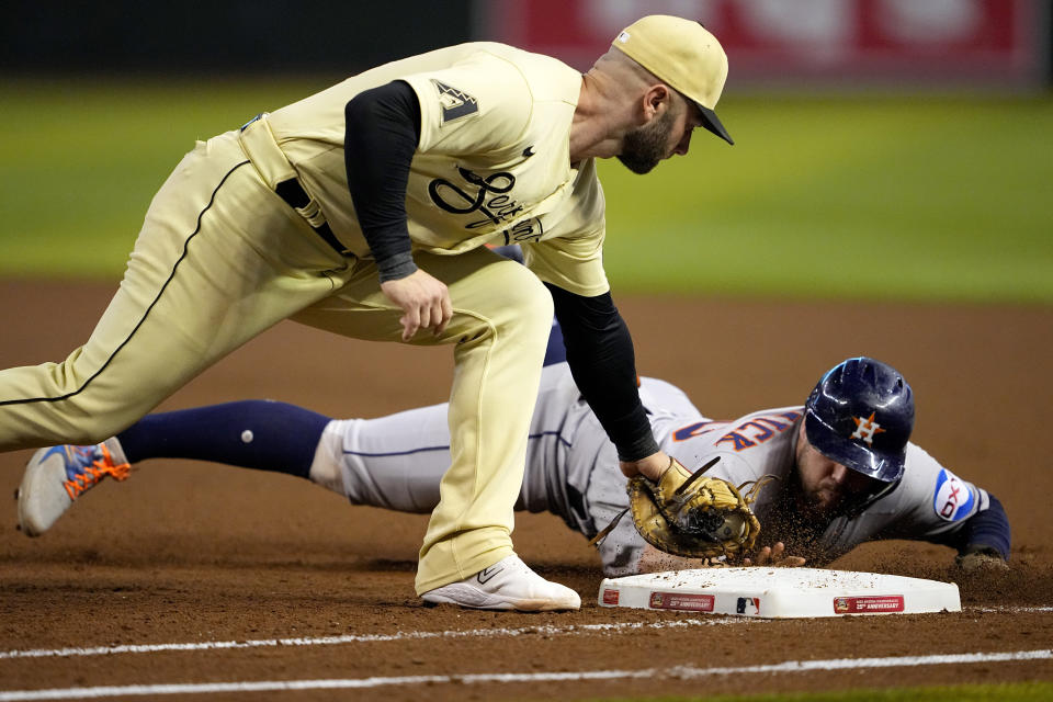 Houston Astros' Chas McCormick is picked-off first by Arizona Diamondbacks' Christian Walker, left, during the seventh inning of a baseball game, Friday, Sept. 29, 2023, in Phoenix. (AP Photo/Matt York)