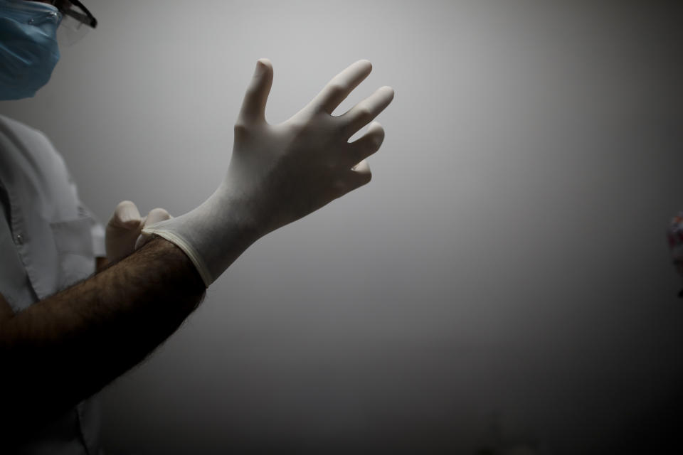 FILE - In this July 18, 2020 file photo, Dr. Matias Norte pulls on rubber gloves at a hospital during a government-ordered lockdown to curb the spread of the new coronavirus in Buenos Aires, Argentina. Argentina reached 1 million confirmed coronavirus cases on Monday, Oct. 19, 2020, according to the Ministry of Health. (AP Photo/Natacha Pisarenko, File)