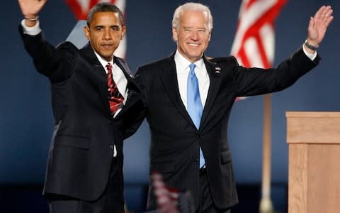 Barack Obama and Joe Biden wave to a crowd of supporters - Credit: REUTERS/Jim Bourg