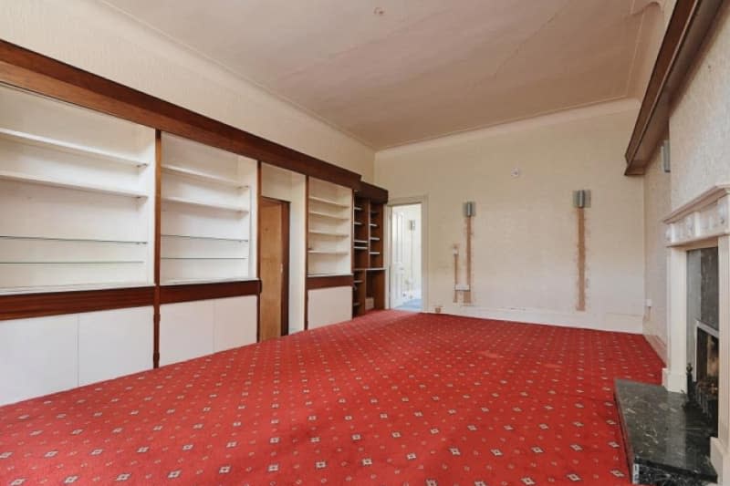 Wood trimmed built-in shelving in light living room with red carpeting.