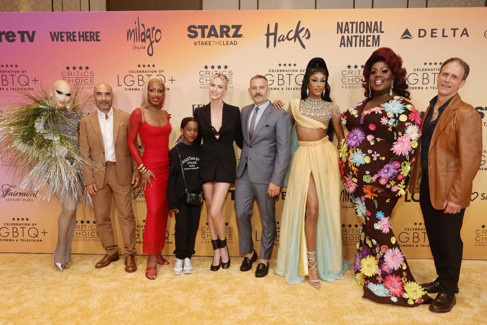 Drag queens pose with Charlize Theron on a yellow carpet at the inaugural Critics Choice celebration of LGBTQ+ talent