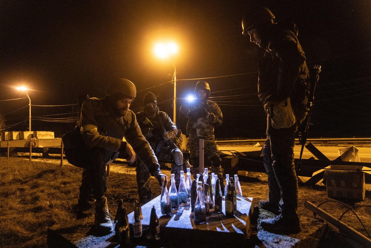 Members of a Territorial Defence unit play checkers with molotov cocktails while guarding a barricade after curfew on the outskirts of eastern Kyiv on March 6, 2022, in Kyiv, Ukraine.