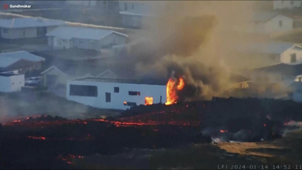 This photo provided by LIVEFROMICELAND.IS shows lava from an erupting volcano in Iceland consuming a building near the town of Grindavik, Iceland, Sunday Jan. 14, 2024. A volcano erupted in southwestern Iceland Sunday for the second time in less than a month, sending semi-molten rock toward a nearby settlement. The eruption just before 8 a.m. came after a swarm of earthquakes near the town of Grindavik, the Icelandic Meteorological Office said. The community was evacuated overnight. (LIVEFROMICELAND.IS via AP)