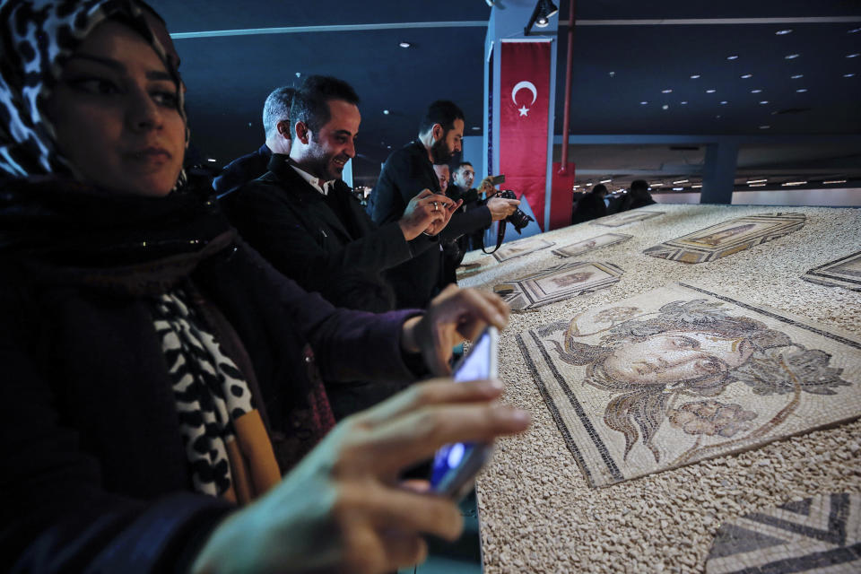 Visitors take pictures of Roman-era mosaics that were part of a U.S. university's art collection and were returned to Turkey, more than half a century after looters smuggled them out, during an exhibition at the Zeugma Mosaic Museum, in Gaziantep, Turkey, Saturday, Dec. 8, 2018. Ohio's Bowling Green State University bought the 12 mosaics from a New York gallery in 1965. Turkish and Bowling Green officials agreed to their return in May 2018. (AP Photo/Emrah Gurel)