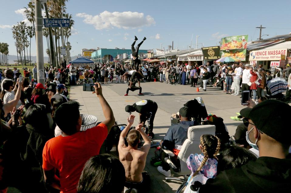 A crowd watches boardwalk performers on Venice Beach on Sunday, Mar. 21, 2021.