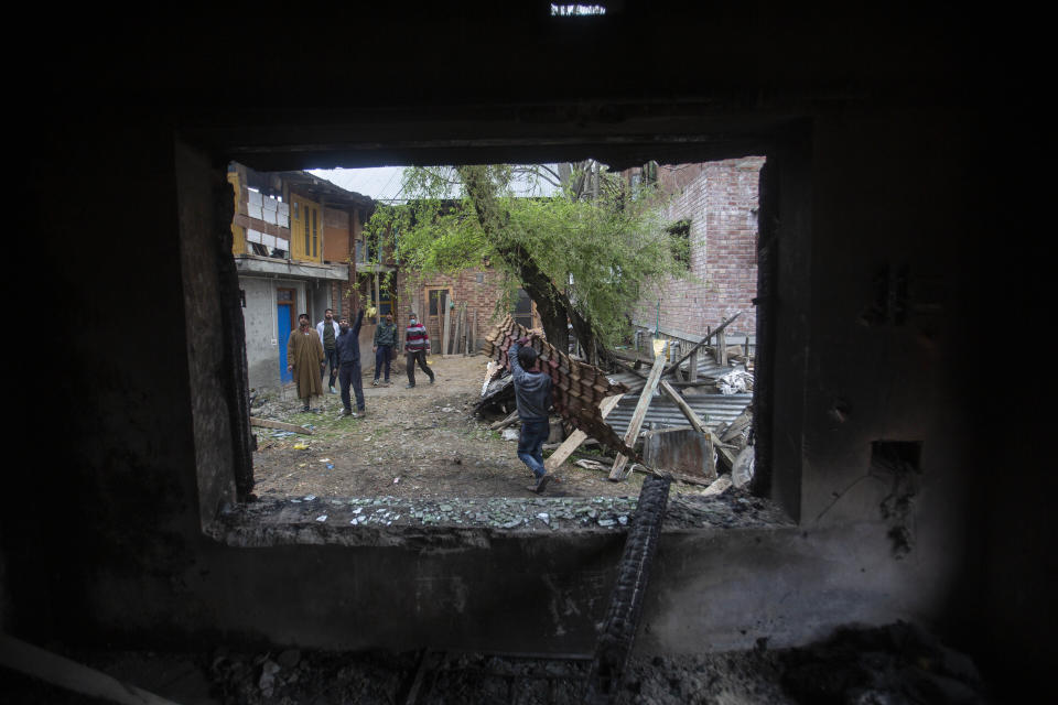 Kashmiri villagers inspect a house that was damaged during a gun battle between government forces and suspected rebels in Bijbehara, some 28 miles (45 kilometers) south of Srinagar, Indian controlled Kashmir, Sunday, April 11, 2021. (AP Photo/Mukhtar Khan)