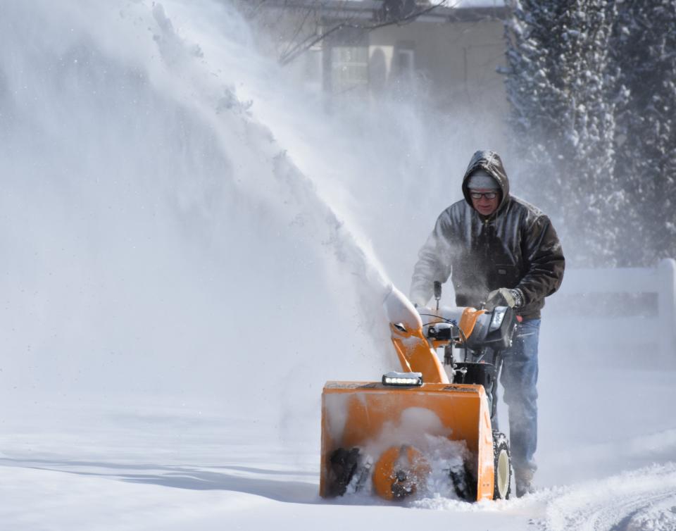 A Windsor, Colo., resident blows snow from a sidewalk Thursday, Dec. 22, 2022, during bitterly cold temperatures. The area received 2 to 4 inches of snow.