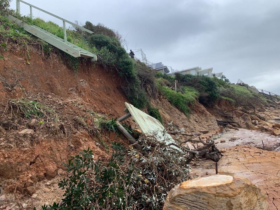 Pictured is a set of stairs leading up to a home hanging off the edge of a cliff.