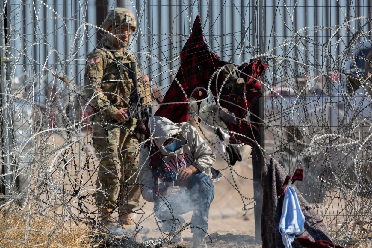 Migrants are escorted south through a border barrier in El Paso by Texas National Guard troops on Thursday. The migrants were seeking to surrender to the Border Patrol.