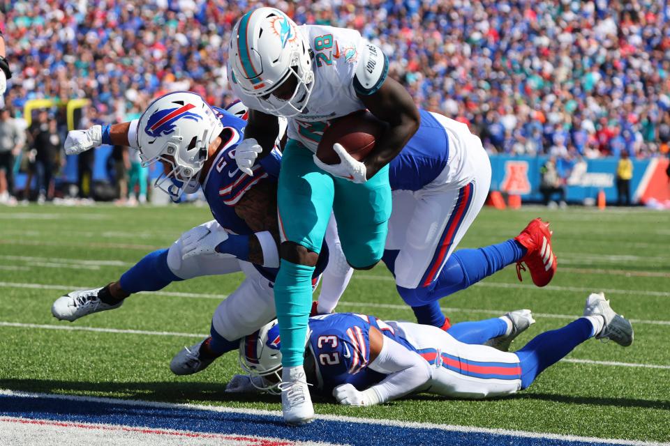 Miami Dolphins running back De'Von Achane (28) eludes Buffalo Bills safety Taylor Rapp, left, and safety Micah Hyde (23), below, as he enters the end zone for a touchdown during the first half an NFL football game, Sunday, Oct. 1, 2023, in Orchard Park, N.Y. (AP Photo/Jeffrey T. Barnes)