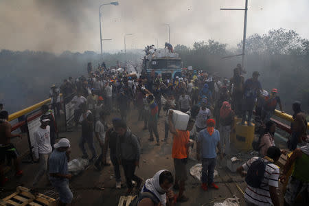 Opposition supporters unload humanitarian aid from a truck that was sent on fire after clashes between opposition supporters and Venezuela's security forces at Francisco de Paula Santander bridge on the border line between Colombia and Venezuela as seen from Cucuta, Colombia, February 23, 2019. REUTERS/Marco Bello