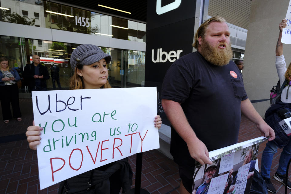 Annette Ribero, left, of San Jose, and Jeff Terry, of Sacramento, hold signs during a demonstration outside of Uber headquarters Wednesday, May 8, 2019, in San Francisco. Some drivers for ride-hailing giants Uber and Lyft turned off their apps to protest what they say are declining wages as both companies rake in billions of dollars from investors. Demonstrations in 10 U.S. cities took place Wednesday, including New York, Chicago, Los Angeles, San Francisco and Washington, D.C. The protests take place just before Uber becomes a publicly traded company Friday. (AP Photo/Eric Risberg)