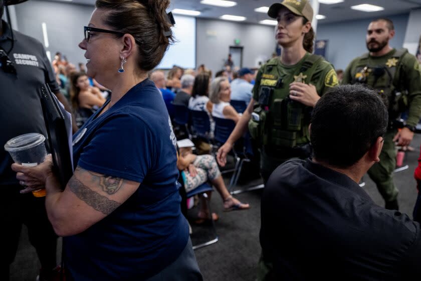 TEMECULA, CA - JULY 18, 2023: Temecula teacher and parent Jennee Scharf is escorted out by Sheriff deputies after she was ejected from the school board meeting by School Board President Joseph Komrosky for calling Board member Danny Gonzalez a "homophobe" on July 18, 2023 in Temecula, California. Gonzalez had previously made unfounded derogatory remarks about Harvey Milk and LBGTQ issues in regards to curriculum.The conservative majority on the school board is at the center of a debate with Gov. Gavin Newsom who has threatened to fine the board over $1 million because of their resistance to include a lesson involving Harvey Milk.(Gina Ferazzi / Los Angeles Times)