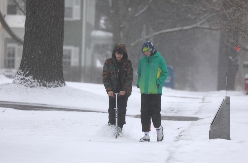 Liam Fuller attempts to ride his scooter on the snowy sidewalk on Main Street in Canandaigua while talking with Anthony Carter. Canandaigua City School District canceled school Tuesday due to the governor declaring Ontario County among the counties under a state of emergency due to wintry weather.