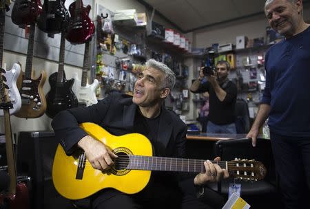 Yesh Atid leader Yair Lapid plays a guitar in a musical instruments store as he campaigns in the southern city of Ashdod March 15, 2015. REUTERS/Ronen Zvulun