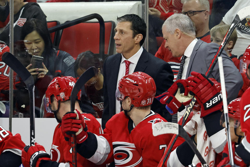 Carolina Hurricanes coach Rod Brind'Amour, back left, watches a replay with assistant coach Jeff Daniels, right, to decide whether to challenge a goal during the second period of Game 2 of the team's NHL hockey Stanley Cup first-round playoff series against the New York Islanders in Raleigh, N.C., Wednesday, April 19, 2023. (AP Photo/Karl B DeBlaker)