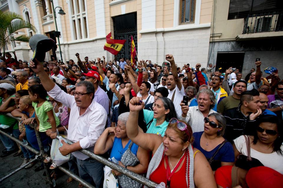 CORRECTS YEAR CHAVEZ WAS ELECTED PRESIDENT - People watch the funeral procession for former Venezuelan Intelligence Chief Eliezer Otaiza as his coffin is carried out of the National Assembly in Caracas, Venezuela, Wednesday, April 30, 2014. Otaiza's body was dumped on the edge of Caracas Saturday after his vehicle was intercepted by a group of armed men. No motive has been established for the crime. As a young army officer, he backed Hugo Chavez's failed 1992 coup attempt and was responsible for his personal security when he was elected president in 1998. (AP Photo/Fernando Llano)