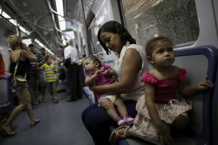 Luana Vieira, four months old, who was born with microcephaly, is held by her mother Rosana Vieira Alves as they ride the subway after a doctor's appointment in Recife, Brazil, February 3, 2016. REUTERS/Ueslei Marcelino/File Photo