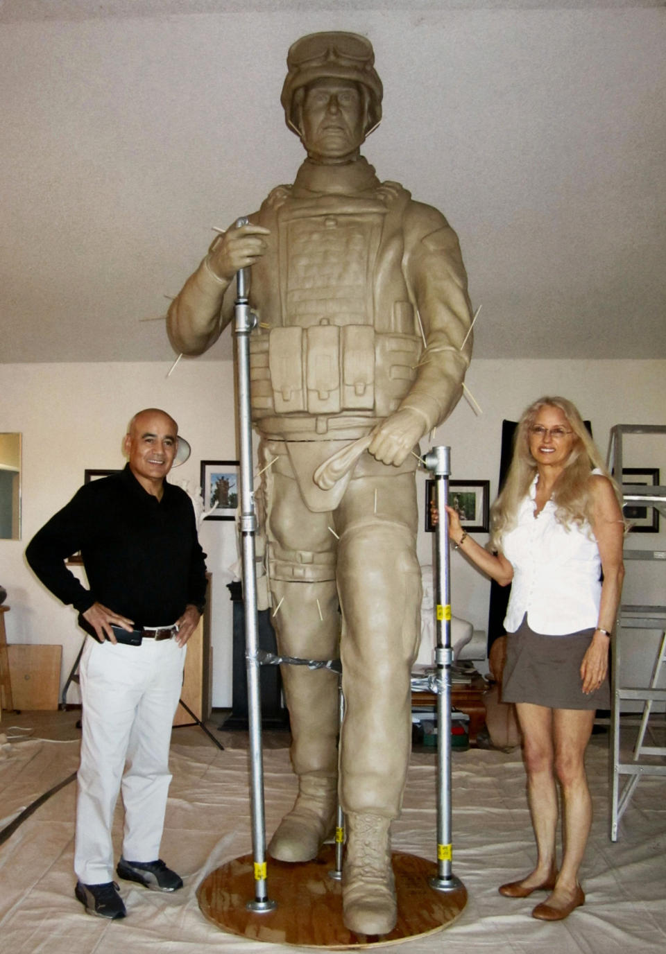 In this Aug. 2, 2012 publicity photo provided by Natural Balance, war handler veteran, author and designer, John Burnam, left, and veteran portrait sculptor, Paula Slater, stand with the silicon bronze 9.5-feet tall military dog handler that is part of the U.S. Working Dogs Teams National Monument shown in the Sculptor's Studio in Hidden Valley Lake, in Calif. (AP Photo/Natural Balance)