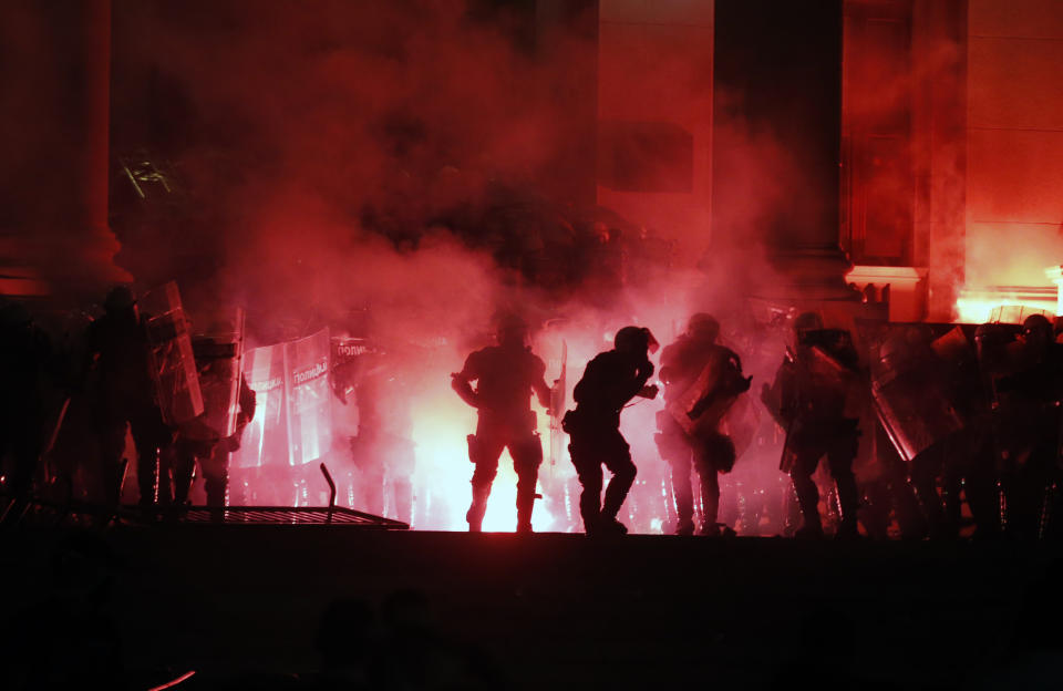 Protesters clash with riot police on the steps of the Serbian parliament during a protest in Belgrade, Serbia, Friday, July 10 2020. Hundreds of demonstrators tried to storm Serbia's parliament on Friday, clashing with police who fired tear gas during the fourth night of protests against the president's increasingly authoritarian rule. (AP Photo/Darko Vojinovic)