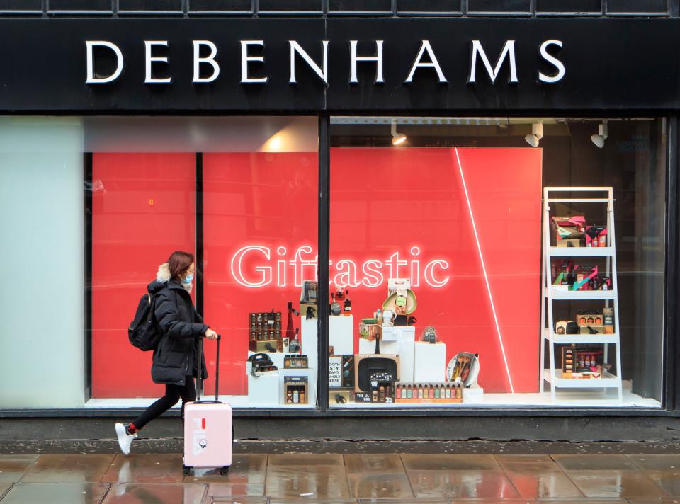 A woman walks past a Debenhams store in Manchester in the final week of a four week national lockdownPA