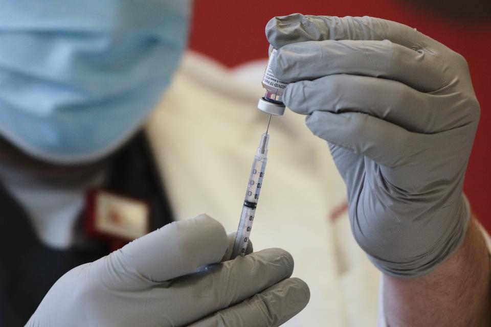 Dr. Stephen Polley draws out a dose of the Pfizer COVID-19 vaccine during distribution to health care workers at Ohio State University Wexner Medical Center East in Columbus, Ohio.