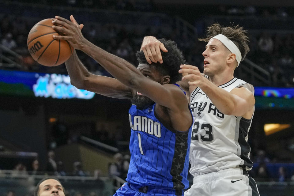 Orlando Magic forward Jonathan Isaac (1) grabs a rebound in front of San Antonio Spurs forward Zach Collins (23) during the second half of an NBA basketball game, Thursday, Feb. 8, 2024, in Orlando, Fla. (AP Photo/John Raoux)