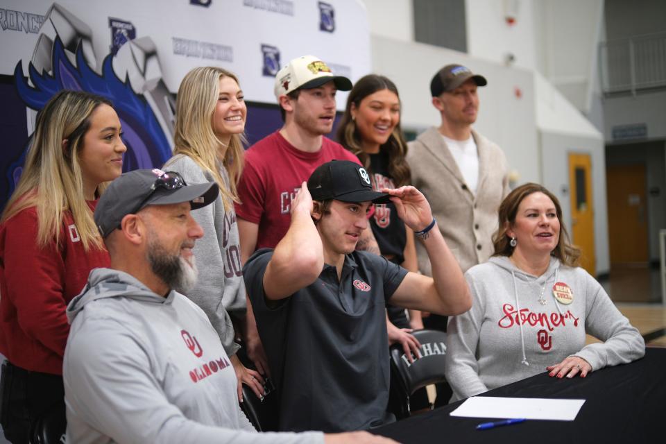 Bethany football standout Taylor Heim celebrates after signing his national letter of intent with the Sooners by putting an OU hat while surrounded by family and friends Friday afternoon in Bethany.