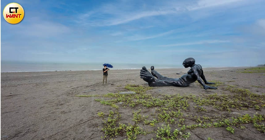 赤腳大足的黑色巨人《行走的意識》，面向大海坐臥在沙灘上。（圖／焦正德攝）