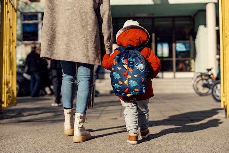 A mother entering kindergarten with her pre-school aged child.