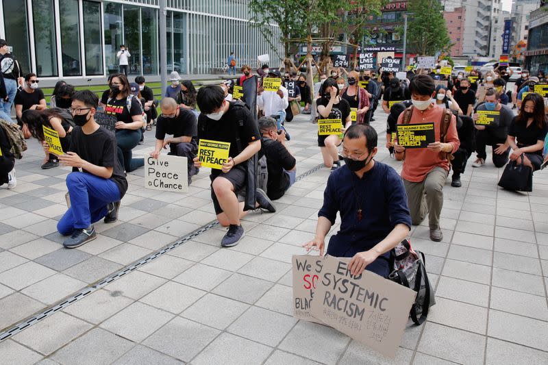 People kneel down as they march on the street in solidarity with protests against the death in Minneapolis police custody of George Floyd in Seoul