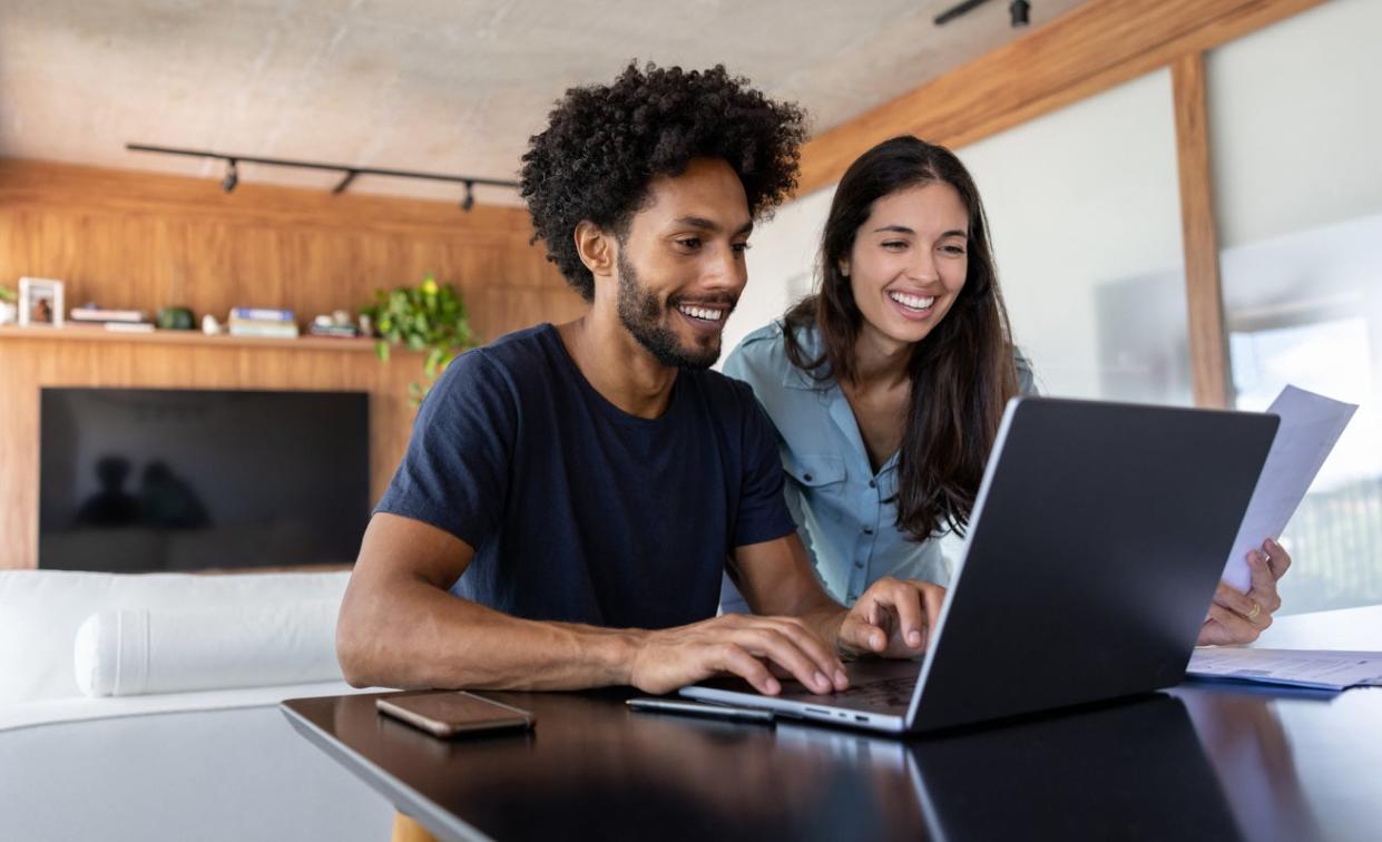 Happy young couple does taxes online.