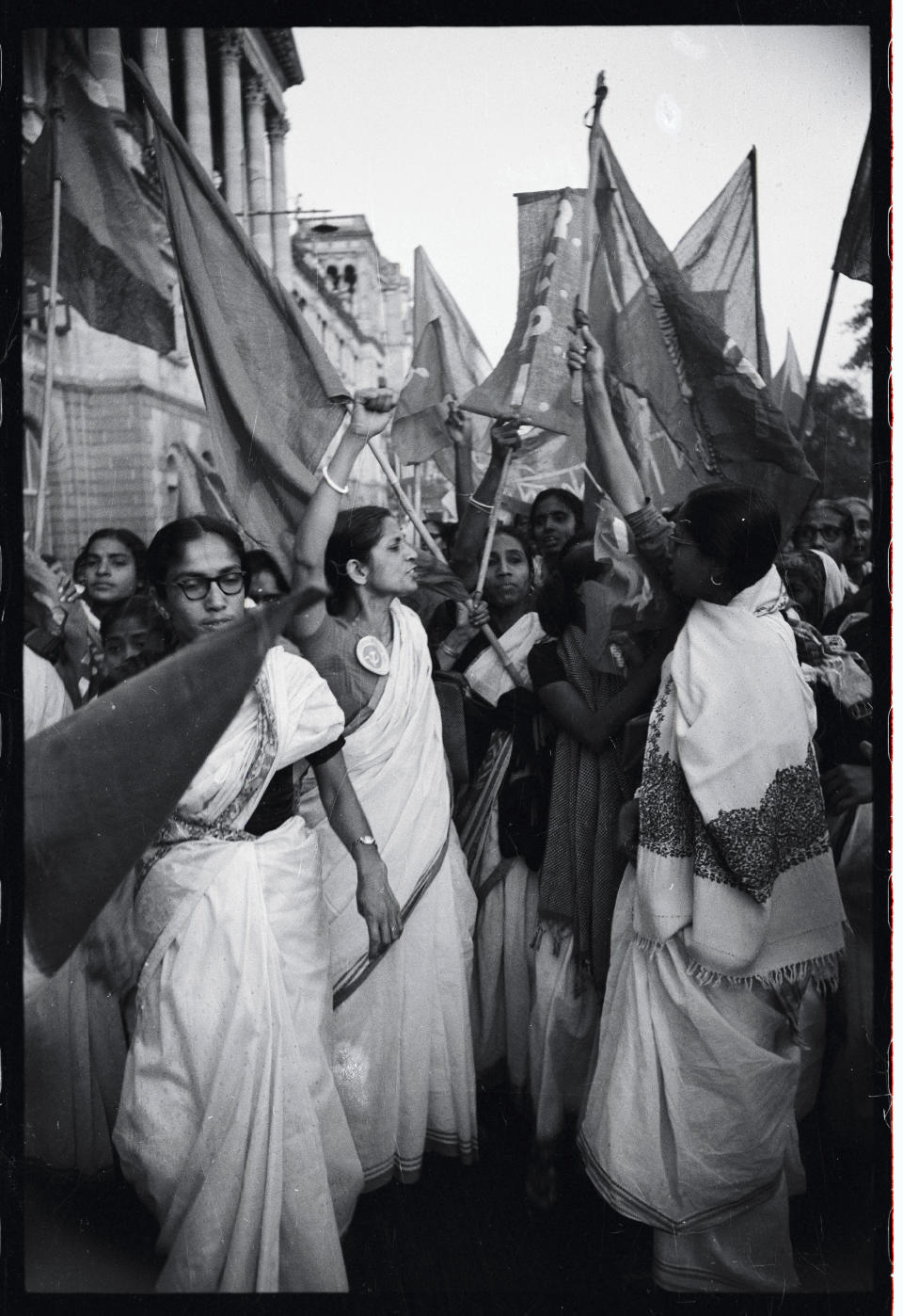 (Original Caption) Flag-carrying, hand-waving, enthusiastic women shout anti-government slogans during a United Front women's Day Demonstration here recently. More than 500 of the active ladies in Calcutta and an equal number in other West Bengal State Districts were arrested for defying the existing ban on public assembly anywhere in the states. The woman in the center wears a button sporting a hammer and sickle, symbol of the Soviet Union.