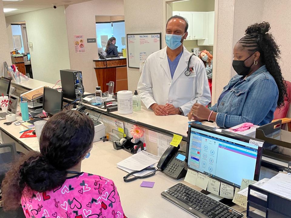 Dr. Ramesh Peramsetty, center, speaks with medical assistants Crystal Cain, standing, and Breanna Wilkins among patients at his Crimson Care clinic on Veterans Memorial Parkway in Tuscaloosa.