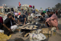 Protesting farmers prepare flat bread for fellow farmers as they block a major highway during a protest against new farming laws they say will result in exploitation by corporations, eventually rendering them landless, at the Delhi-Haryana state border, India, Tuesday, Dec. 1, 2020. The busy, nonstop, arterial highways that connect most northern Indian towns to this city of 29 million people, now beat to the rhythm of never-heard-before cries of "Inquilab Zindabad" ("Long live the revolution"). Tens and thousands of farmers, with colorful distinctive turbans and long, flowing beards, have descended upon its borders where they commandeer wide swathes of roads. (AP Photo/Altaf Qadri)